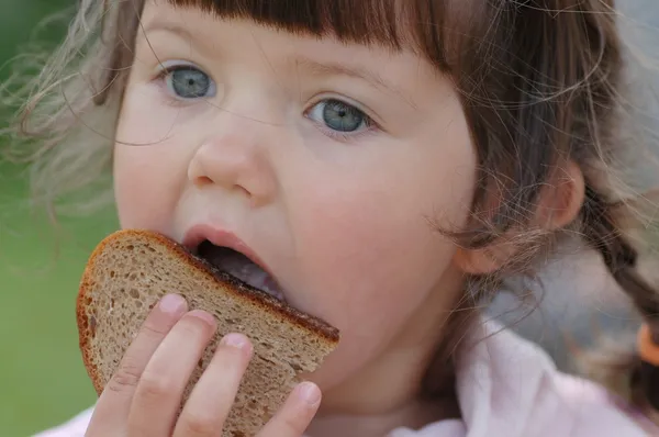 Mooie baby, eten brood Stockfoto