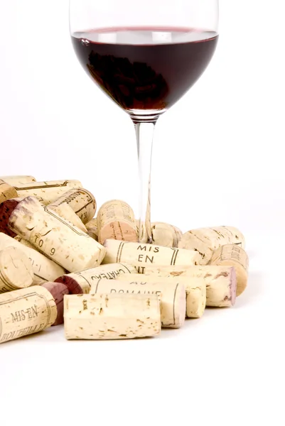 Glas rött vin bland korkar — Stockfoto
