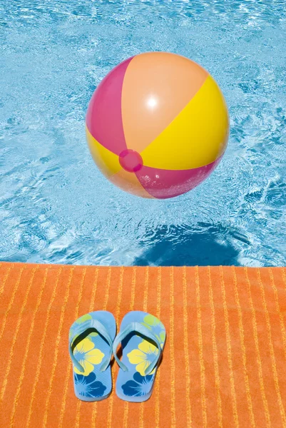 Strandbal drijvend in een zwembad en flip-flops — Stockfoto