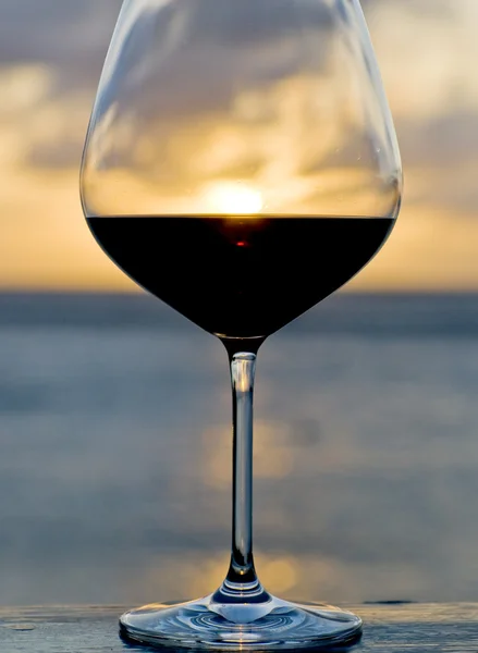 Bir bardak kırmızı şarap arkasında günbatımı — Stok fotoğraf