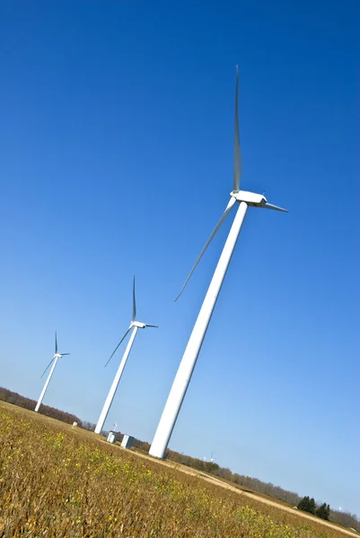 Strømproduktion vindmøller mod den blå himmel i et felt - Stock-foto