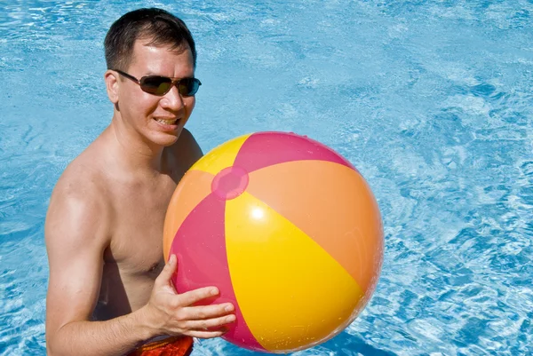 Hombre sosteniendo una pelota de playa en una piscina —  Fotos de Stock