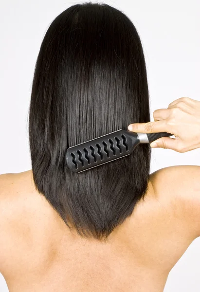 Mulher escovando em linha reta cabelo preto — Fotografia de Stock