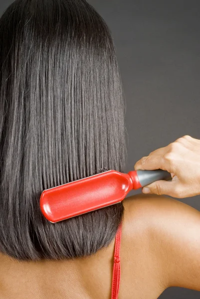Mulher escovando seu cabelo preto reto — Fotografia de Stock