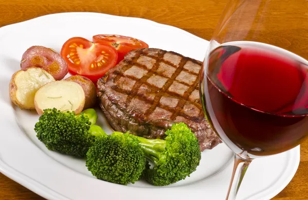 Bife de costela grelhado servido com legumes e um copo de vinho tinto — Fotografia de Stock