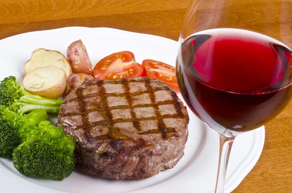 Gegrilltes Rib Eye Steak serviert mit Gemüse und einem Glas Rotwein Stockfoto