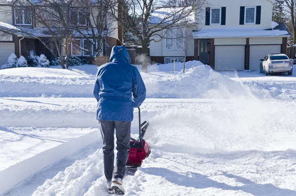 Человек использует снегоочиститель, чтобы очистить снег — стоковое фото