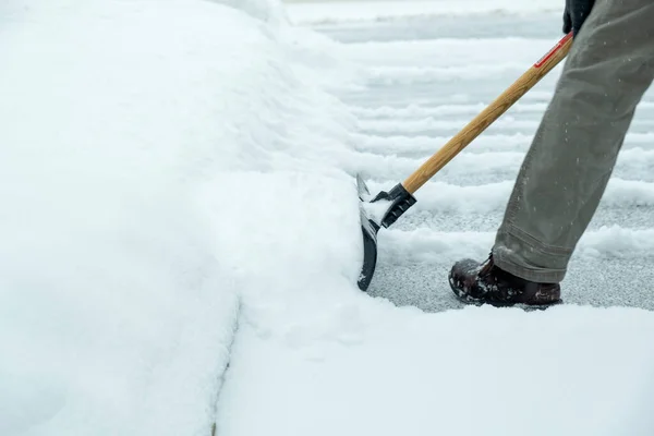 ドライブウェイからショベルで雪を取り除く男 — ストック写真