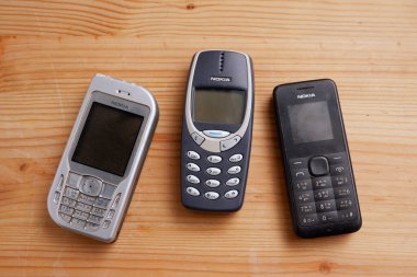 Bangkok, Tayland - 17 Kasım 2021 Birçok Nokia cep telefonu modeli 3310 ve diğer düğmeli telefonları ahşap zemin üzerinde kullandı