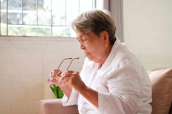 Oudere Aziatische Vrouw Met Grijs Haar Kijkt Houdt Haar Bril — Stockfoto