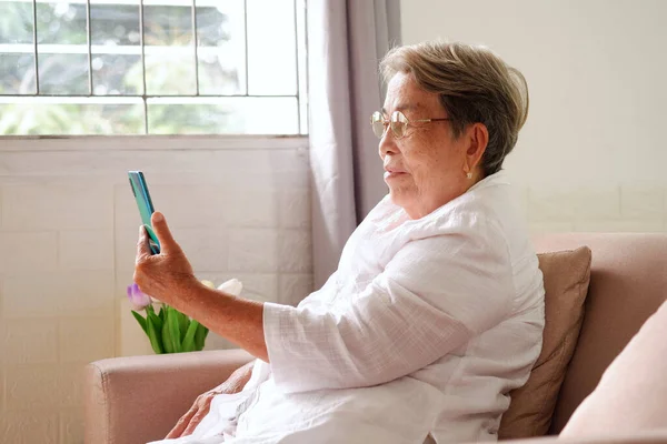 白髪のアジア系のお年寄りが笑顔で携帯電話を使っています 高齢化社会悲しいと孤独な概念 テキストのためのコピースペースと ロイヤリティフリーのストック写真