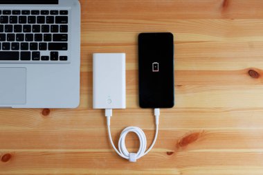 Powerbank giriş telefonundan USB şarj aleti ya da ahşap zemindeki akıllı telefon ve laptop bilgisayarı, Üst Görünüm.