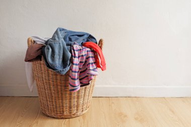 Bir sürü kullanılmış giysi taşıyan ve onları yıkamaya hazırlayan ahşap hasır sepet..