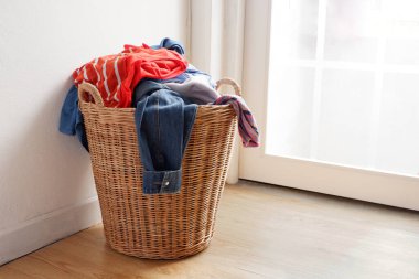 Bir sürü kullanılmış giysi taşıyan ve onları yıkamaya hazırlayan ahşap hasır sepet..