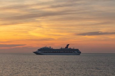 Meksika Körfezi - 5 Nisan 2020: Karnaval Valor 'un denize demir atması. Arka planda güzel gün batımı turuncu gökyüzü ve ön planda sakin okyanus.