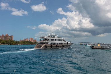 Nassau, Bahamalar - 14 Mayıs 2019: Loon yatı Nassau limanında seyrediyor. Turkuaz su ön planda. Atlantis tatil köyü, arka planda mavi bulutlu gökyüzü.