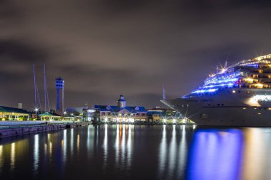 Nassau, Bahamalar - 6 Temmuz 2019: Güzel Karnaval Özgürlük yolcu gemisi gece Prens George Wharf 'a yanaştı. Liman suyunda ışık yansımaları. Arka planda liman binaları var. Uzun pozlama.