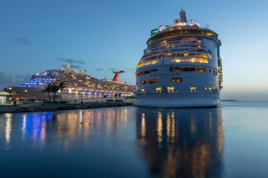 Nassau, Bahamalar - 13 Temmuz 2019: Deniz Piyadeleri Prensi George Rıhtımı 'nda gün batımında vuruldu. Mavi saat. Ön plandaki suda muhteşem ışık yansımaları var. Arka planda Özgürlük Karnavalı.