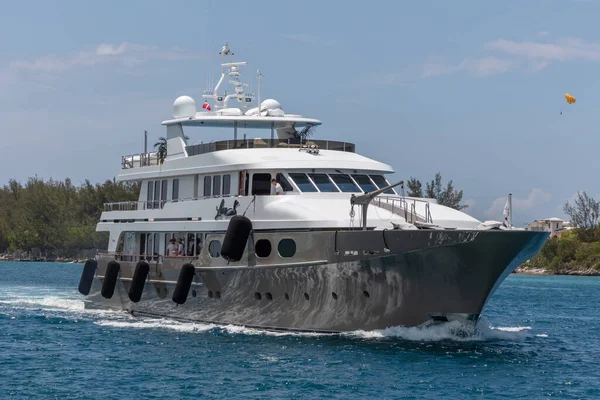 Nassau, Bahamalar - 14 Mayıs 2019: Nassau limanında Loon yatı. Bazı mürettebat açık güvertelerde. Ön planda turkuaz su var. Arkaplanda kıyı çizgisi ve mavi bulutlu gökyüzü.