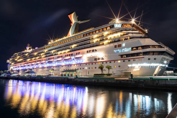 巴哈马拿骚 Nassau Bahamas 2019年6月16日 美丽的低角度拍摄的嘉年华自由号游轮夜间停泊在乔治王子码头 浅浅的倒影在港湾水面上的前景 图库照片