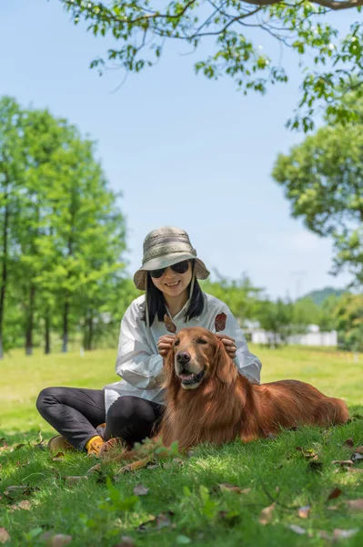 Golden Retriever Towarzyszy Właścicielowi Siedzenia Trawie Parku — Zdjęcie stockowe