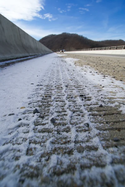 Voiture trace des marques de pneus dans la neige sur le pont de passage supérieur — Photo