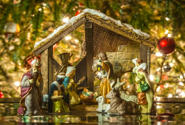 Old handmade nativity scene in front of a christmas tree — Stock Photo, Image