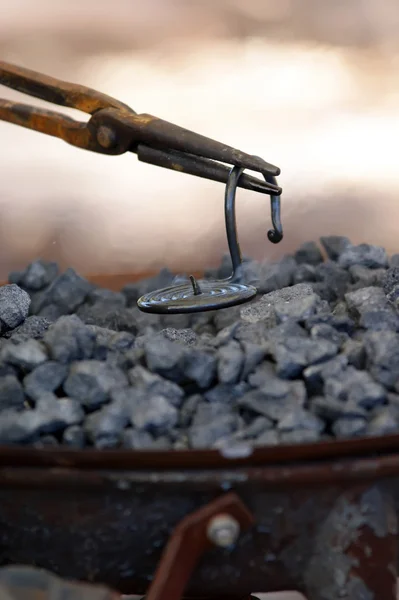 Железный кузнец, работающий рядом с горячим углем — стоковое фото
