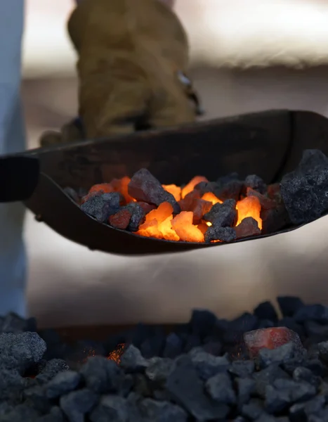 Herrero de hierro trabajando cerca de carbón caliente — Foto de Stock