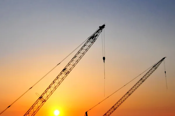 Grúas de construcción industrial y siluetas de construcción sobre el sol — Foto de Stock