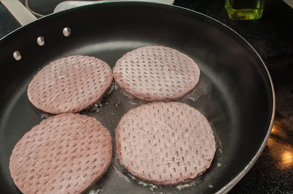 Four hamburgers on frying pan — Stock Photo, Image