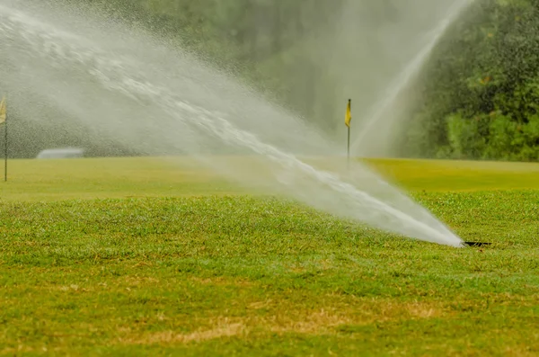 Vattning grönt gräs gräsmatta på golfbana — Stockfoto