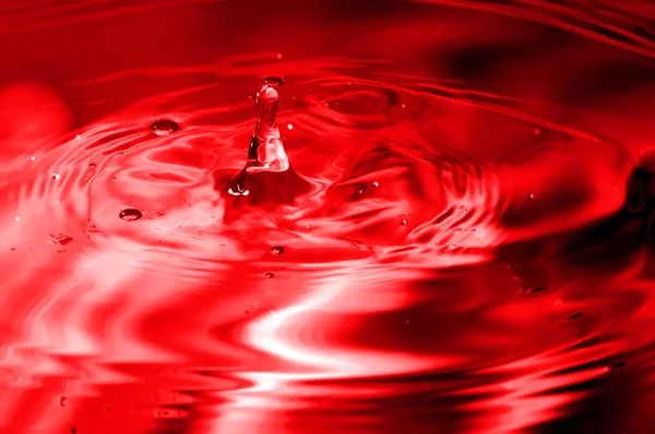 Röd multi färgade vatten droppe bubblande — Stockfoto