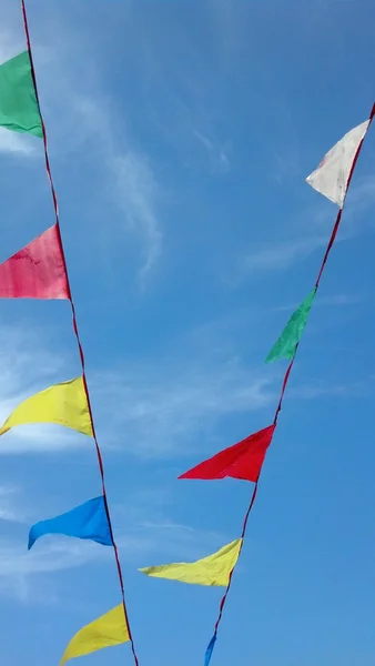 Multicolored rainbow flags on continuous string on blue clear sky — Stock Photo, Image