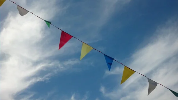 Multicolored rainbow flags on continuous string on blue clear sky — Stock Photo, Image