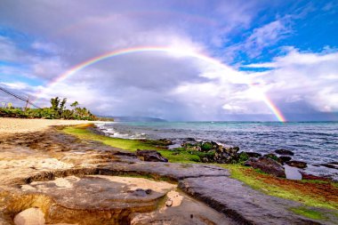 Sunset Beach, Oahu, Hawaii 'deki popüler sörf yerinin üstünde gökkuşağı.