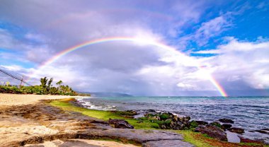 Sunset Beach, Oahu, Hawaii 'deki popüler sörf yerinin üstünde gökkuşağı.