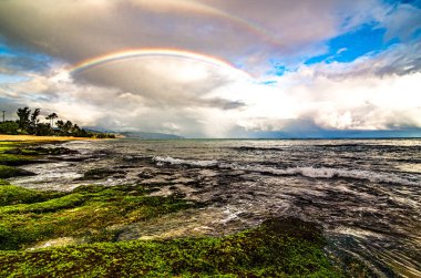 Sunset Beach, Oahu, Hawaii 'deki popüler sörf yerinin üstünde gökkuşağı.