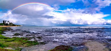 Sunset Beach, Oahu, Hawaii 'deki popüler sörf yerinin üstünde gökkuşağı.