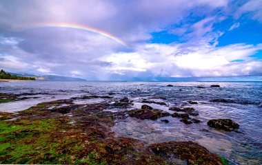 Sunset Beach, Oahu, Hawaii 'deki popüler sörf yerinin üstünde gökkuşağı.