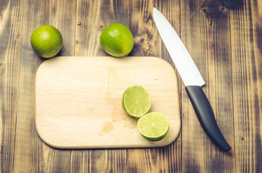 Tahta bir masada dilimlenmiş limon ve bıçaklı beyaz bir bıçak.. 