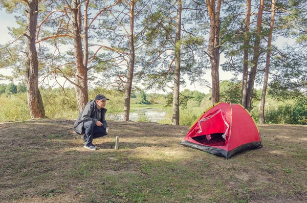 Man camping near the tent in the forest. Rest at nature.