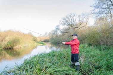 Balıkçı nehre bir olta atar. Spor balıkçılığı.