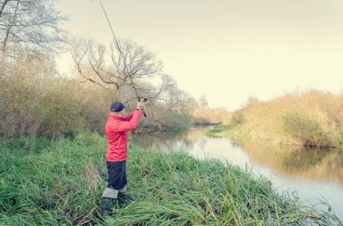 Balıkçı nehre bir olta atar. Spor balıkçılığı.