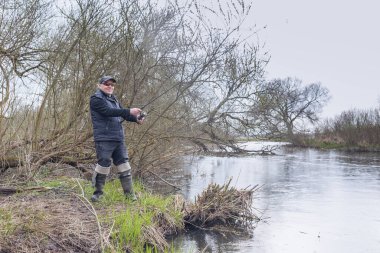 Balıkçı, nehrin üzerinde duran bir oltayla bir balık çeker. Erkek hobisi.