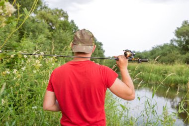 Elinde olta olan bir balıkçı. Arkadan bak..