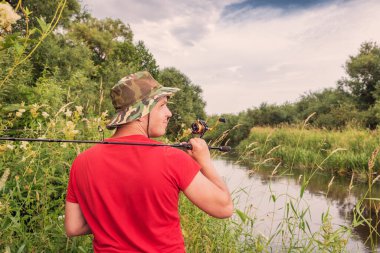 Elinde olta olan bir balıkçı. Arkadan bak..