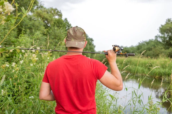 Elinde olta olan bir balıkçı. Arkadan bak..