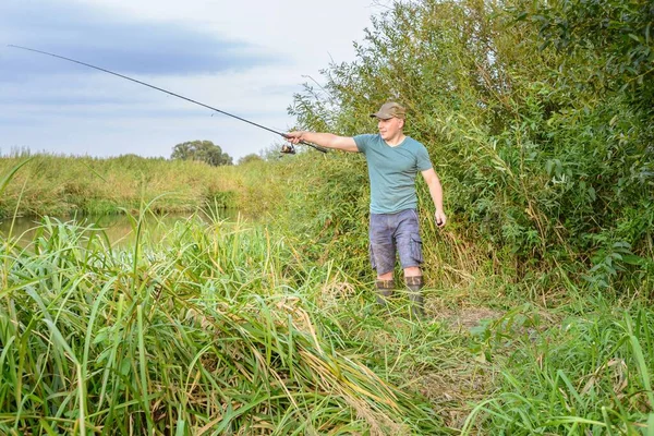川のほとりに釣竿を持ったハンサムな若い男 アウトドアスポーツ — ストック写真