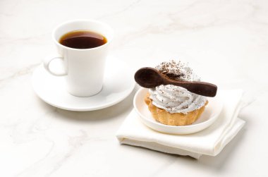 Sütlü beyaz proteinli kek sepeti beyaz bir tabakta çikolata kaşığı ve bir fincan kahveyle süslenmiş. Tatlı teması. 